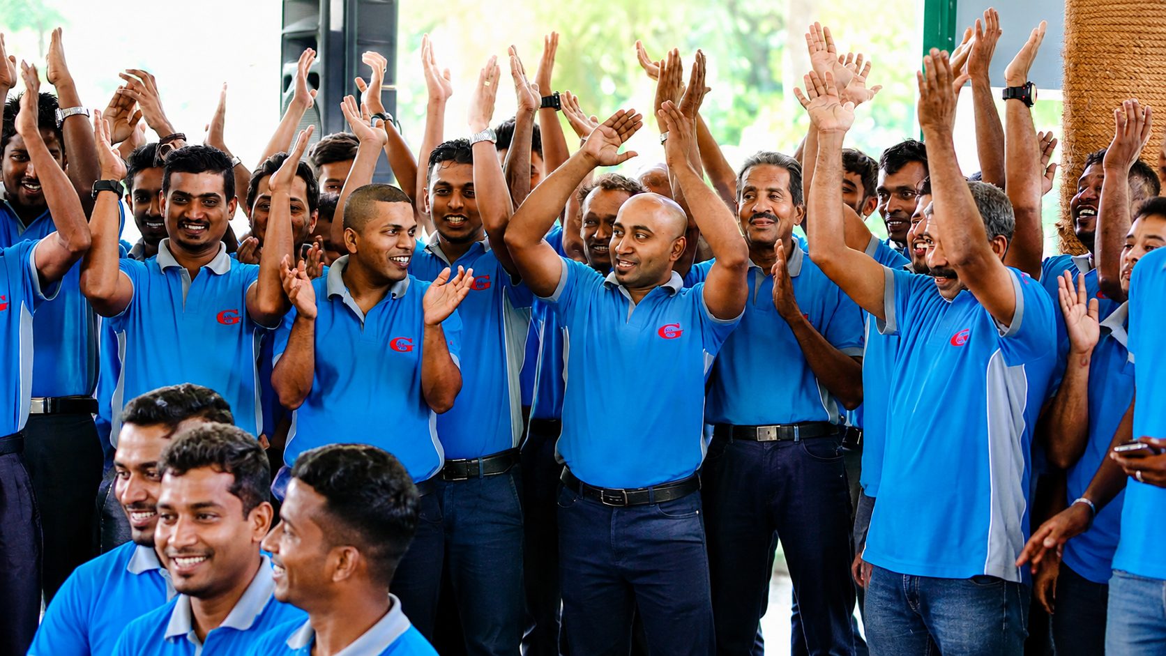 The A.R.G team in blue company shirts, smiling and clapping together